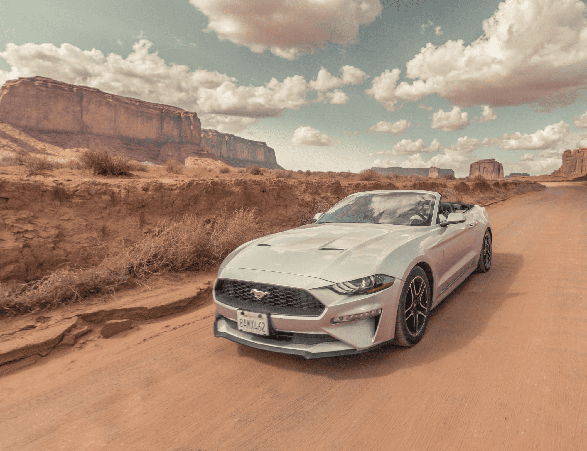 Ford Mustang driving on dirt road.